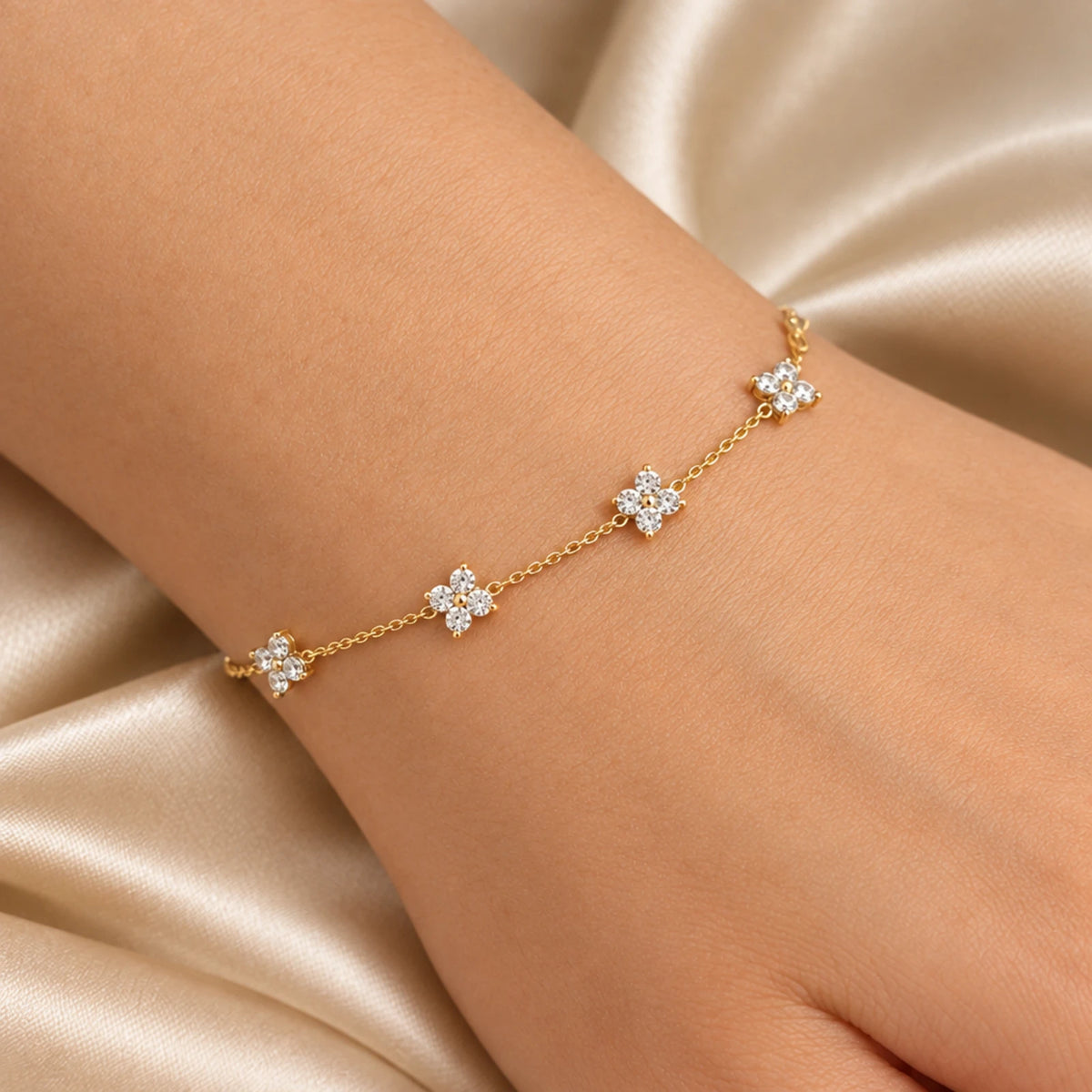 Close-up of the Clover Zircon Station Bracelet worn on the wrist, gold tone chain with zircon clovers