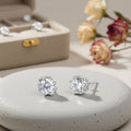 Zircon glow stud earrings on a stone podium beside a jewelry box and dried flowers
